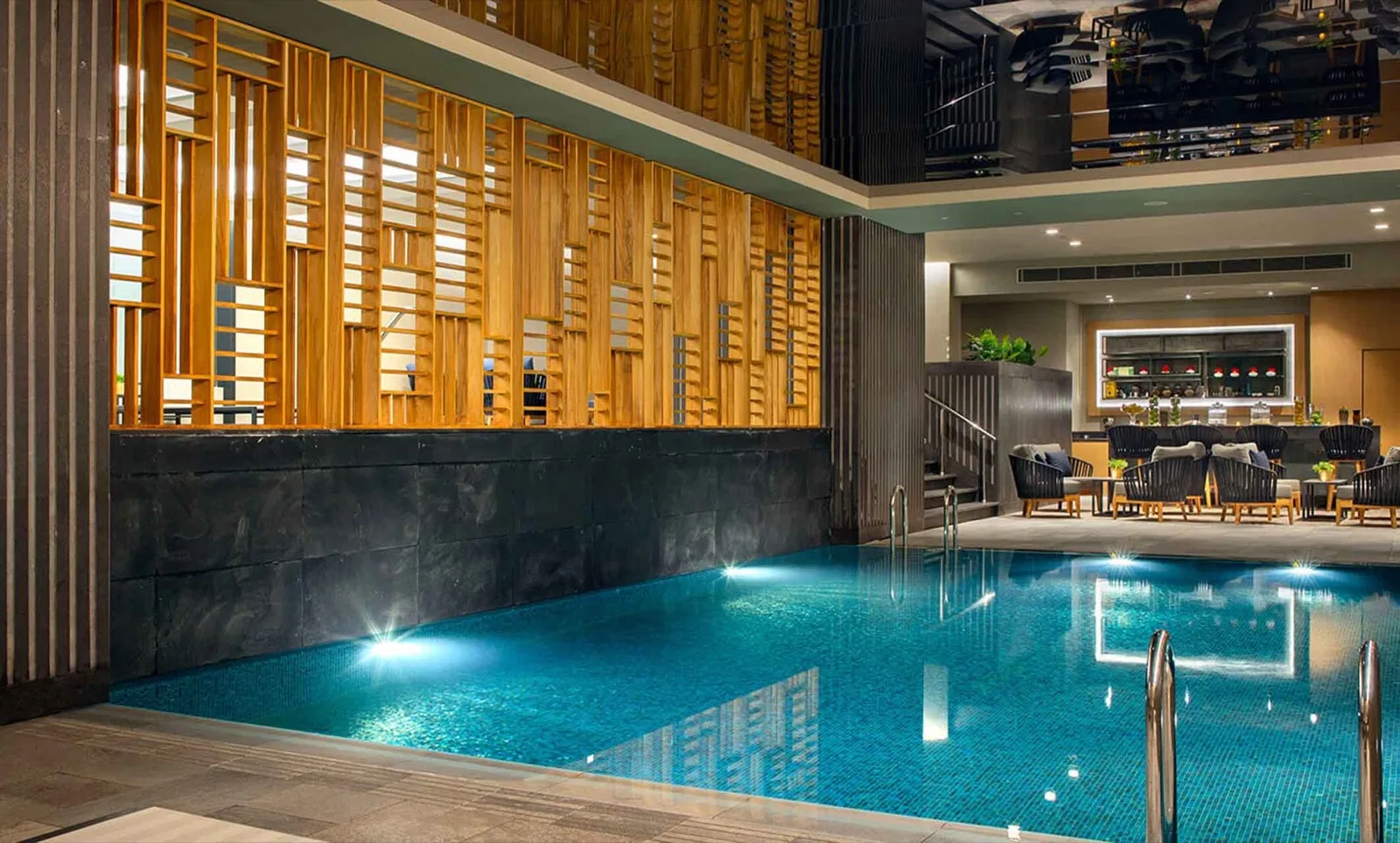 Otel kapalı havuzu, ahşap lata duvar ve gece aydınlatması