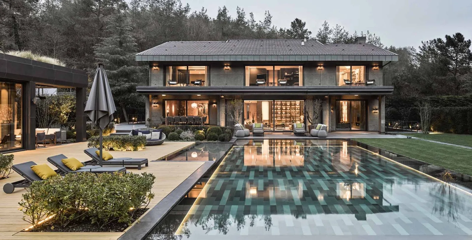 Akşam ışığında villa bahçesinde uzun taşmalı havuz
