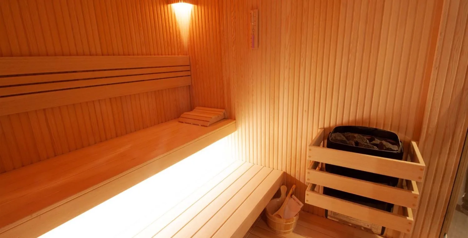 Sauna, açık renk lata kaplama ve gömme taş ısıtıcı