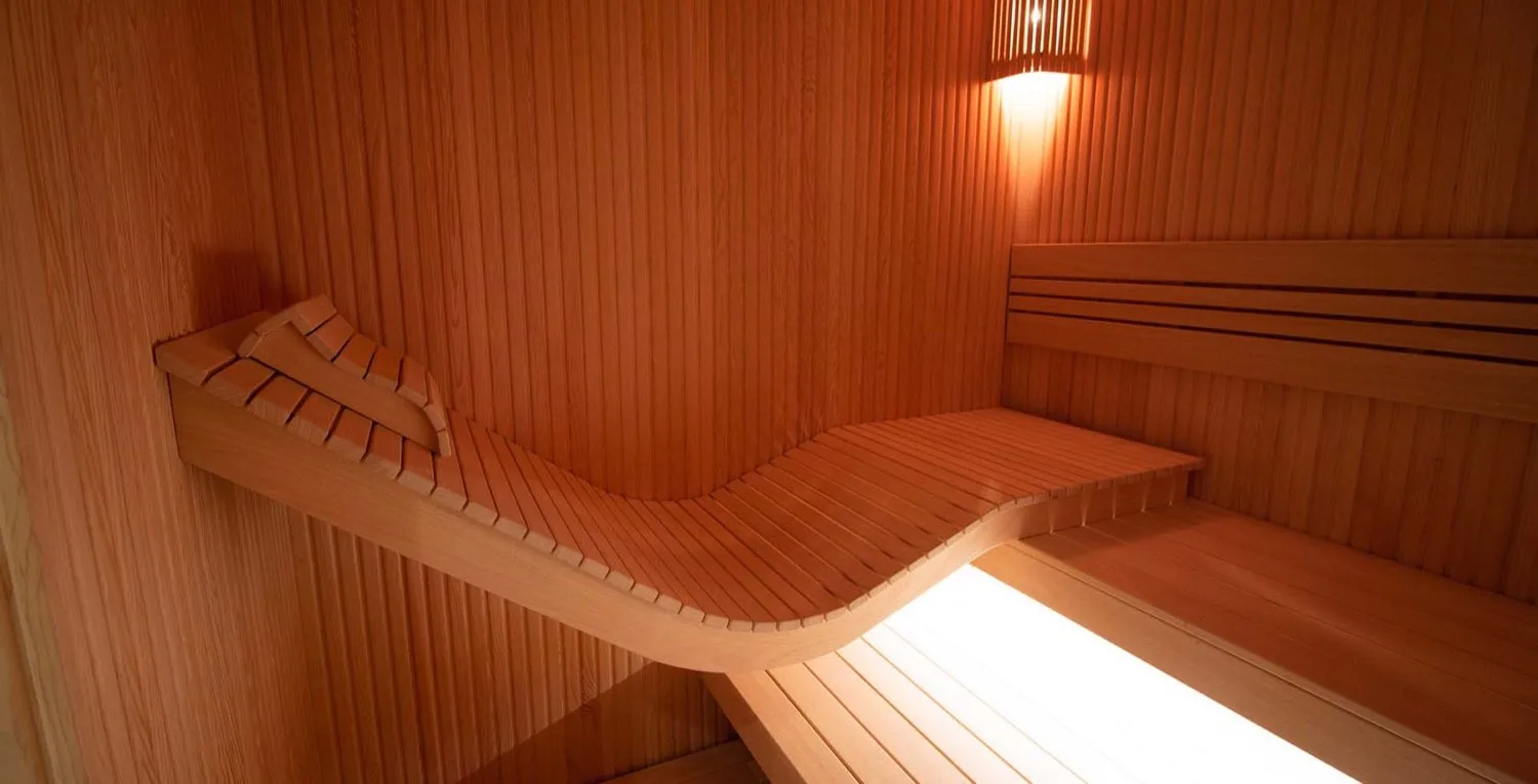Sauna, kavisli uzanma bankı ve sıcak ahşap ton