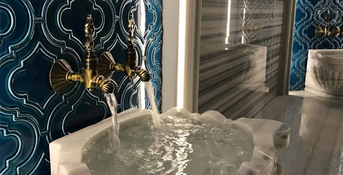 Oran Hotel hamamında altın musluklu kurna ve çini pano